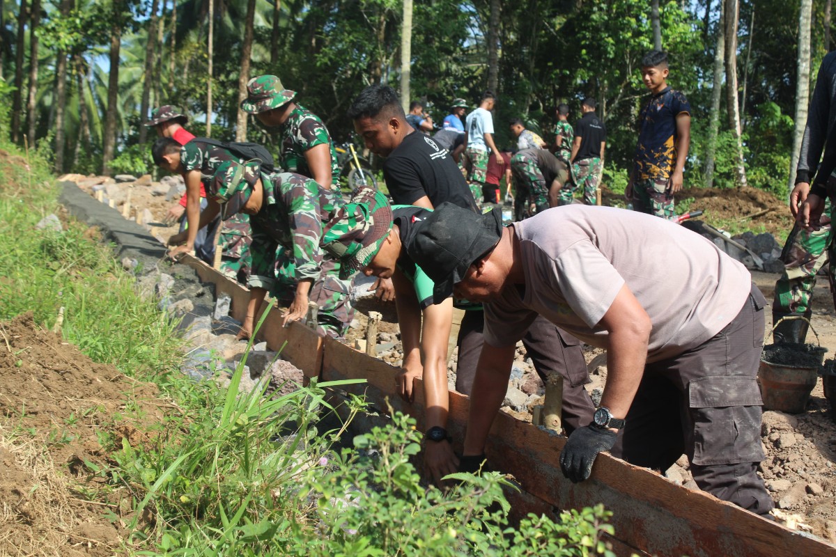 Satgas TMMD Kodim Manado bersama warga Bengkol gotong royong dalam pembangunan jalan dan perbaikan rumah.