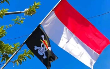 Bendera bajak laut One Piece dikibarkan berdampingan dan lebih tinggi dari bendera Merah Putih saat perayaan bulan kemerdekaan.